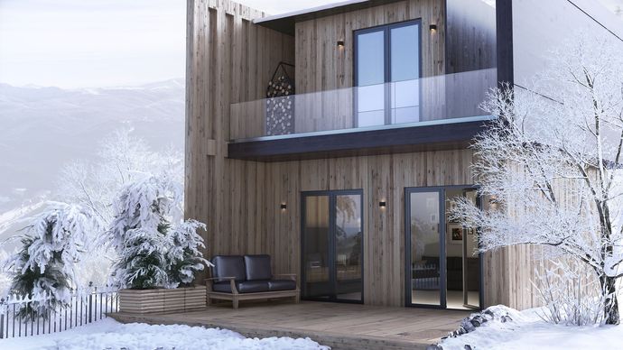 A wooden house with a balcony is surrounded by snow and trees.