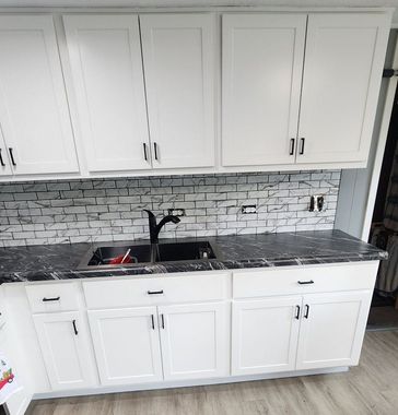 Kitchen remodel with a new brass water faucet, cabinets, granite countertop, and white tile floors.