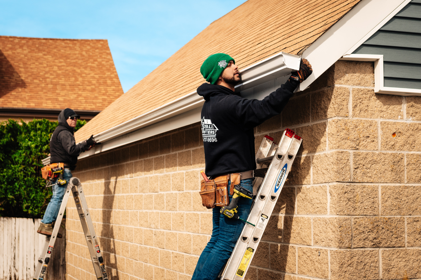 Two men are working on the side of a house.