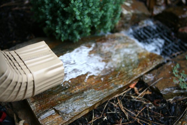 Water is coming out of a gutter on a rock.