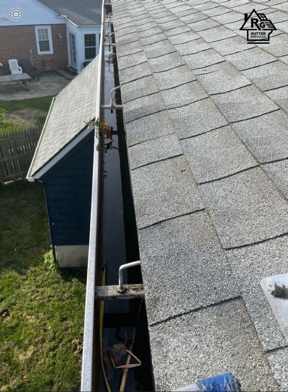 A gutter is sitting on top of a roof next to a house.