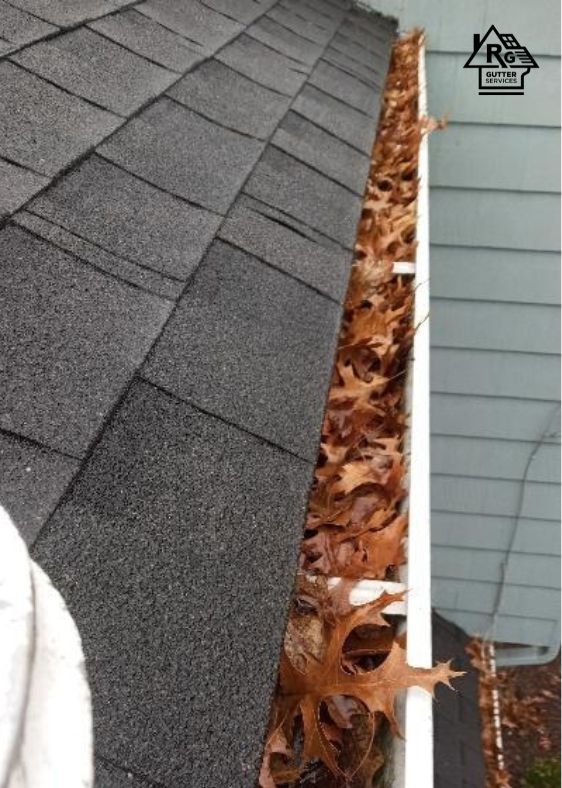 A gutter filled with leaves on the side of a house