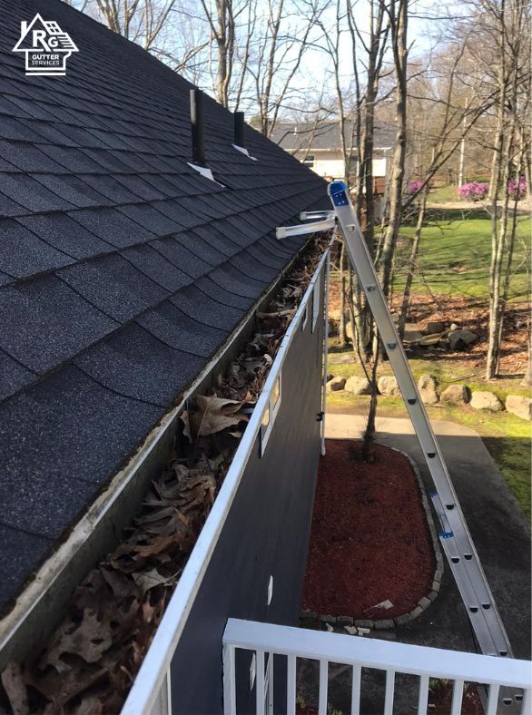 A ladder is attached to a gutter on the side of a house.