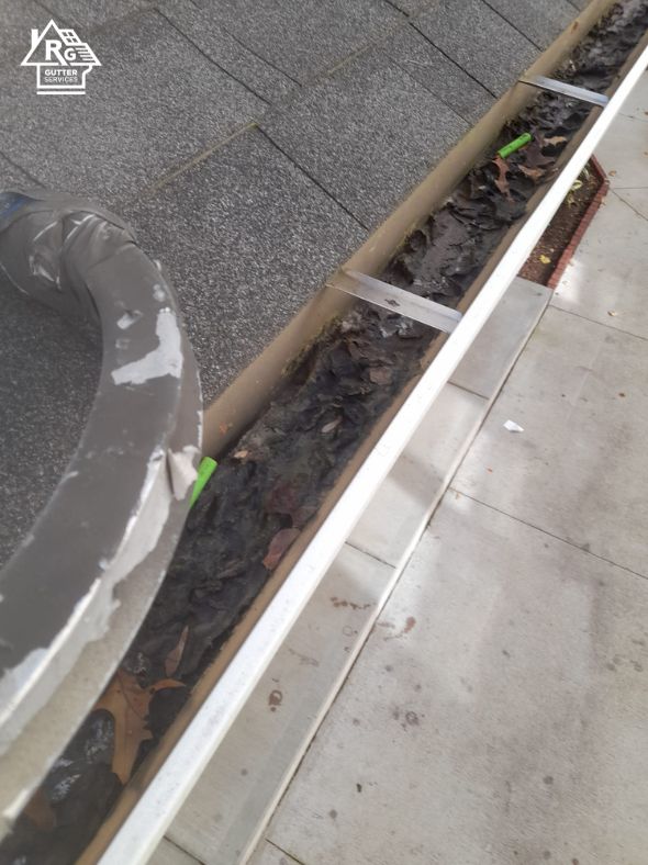 A close up of a gutter with leaves on it.