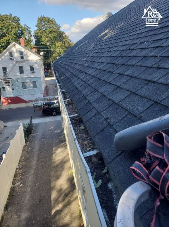 A person is cleaning a gutter on the roof of a house.