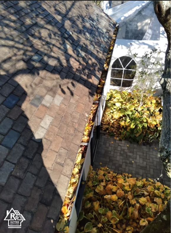 An aerial view of a gutter with leaves on it and a white tent in the background.
