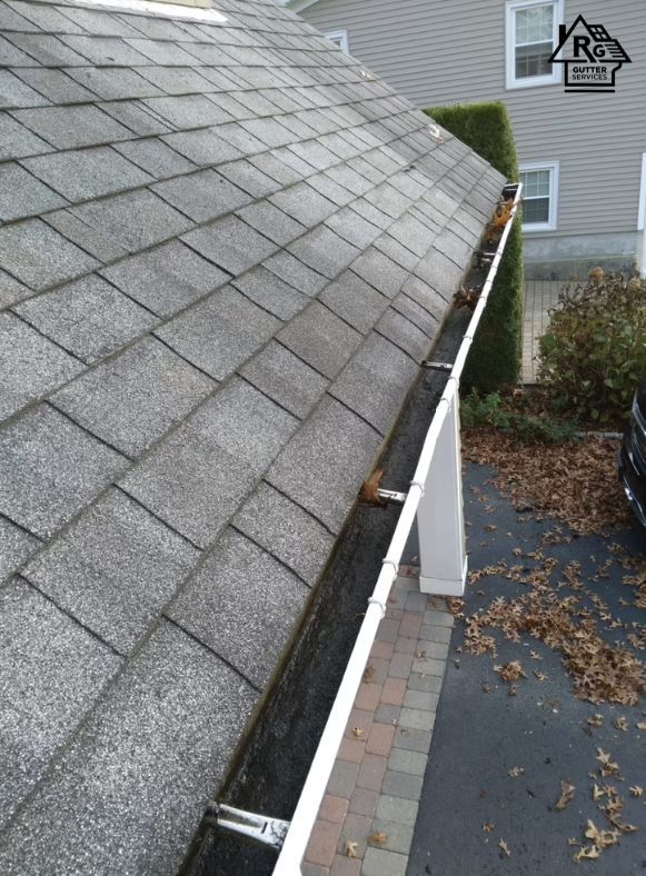 A gutter on the side of a roof next to a driveway.