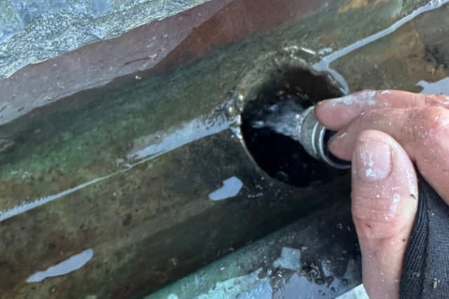 A person is cleaning a pipe with a hose.