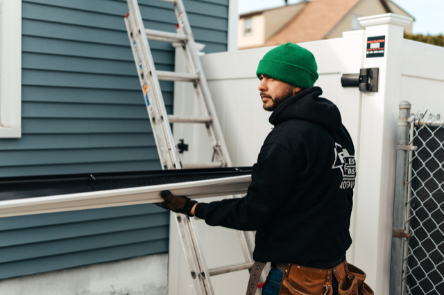 A man is standing on a ladder next to a house.