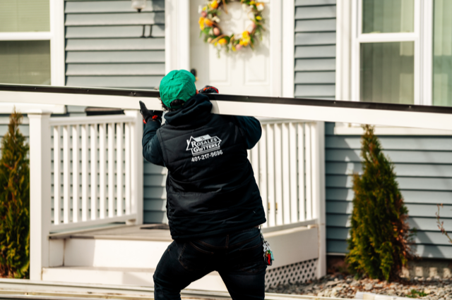 A man is standing in front of a house with a wreath on the door.