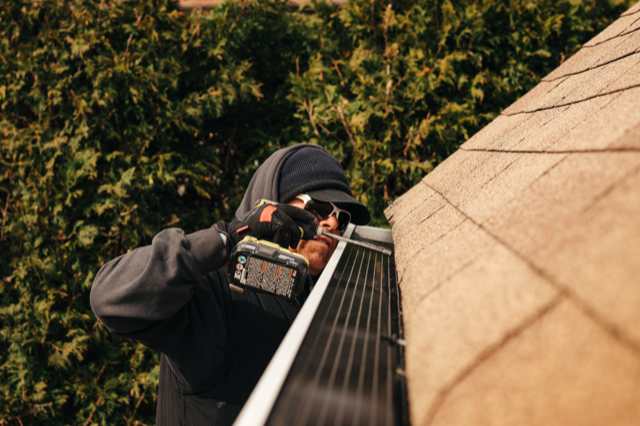 A man is working on a solar panel on the roof of a house.