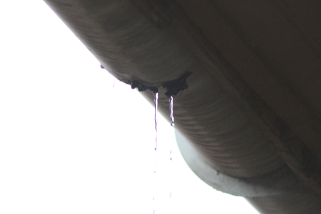 A close up of a gutter with water dripping from it