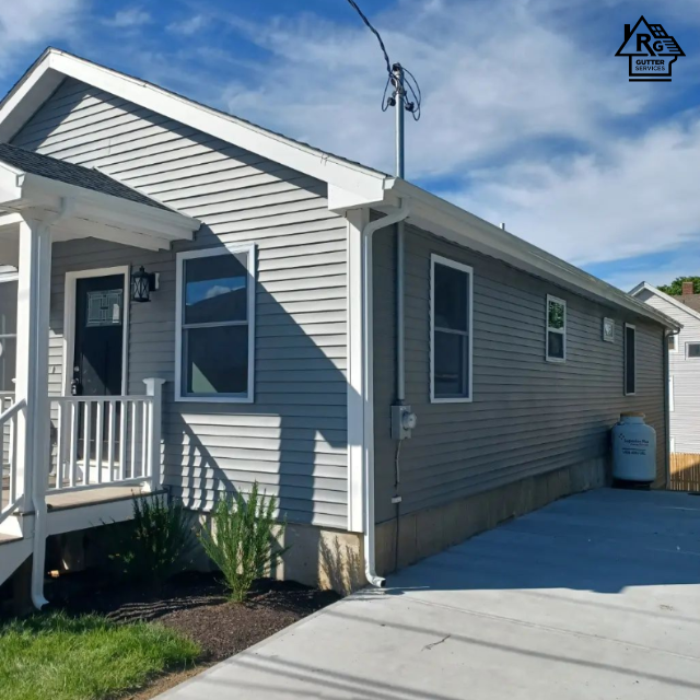 A gray house with a white porch has a r on it