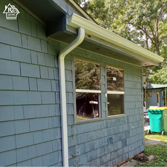 A blue house with a white gutter and a window