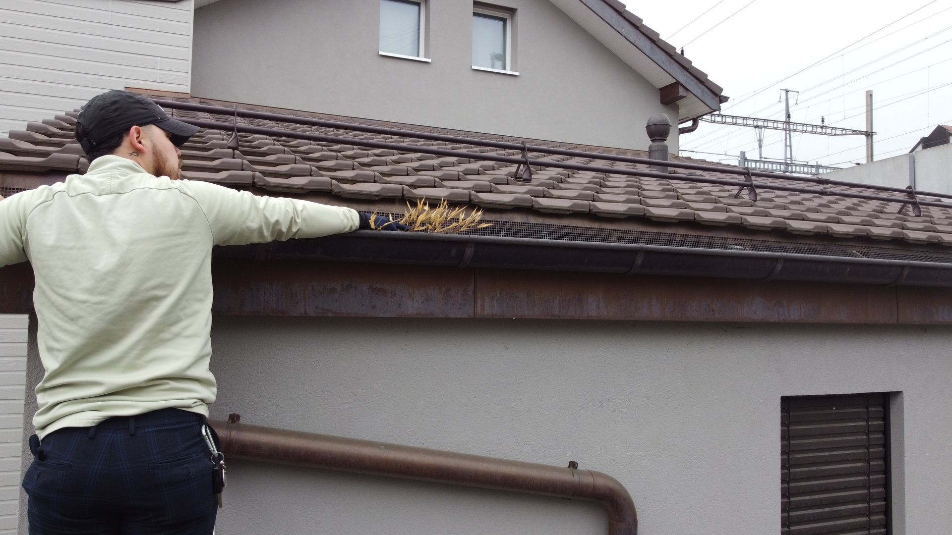 A man is cleaning the gutters of a house