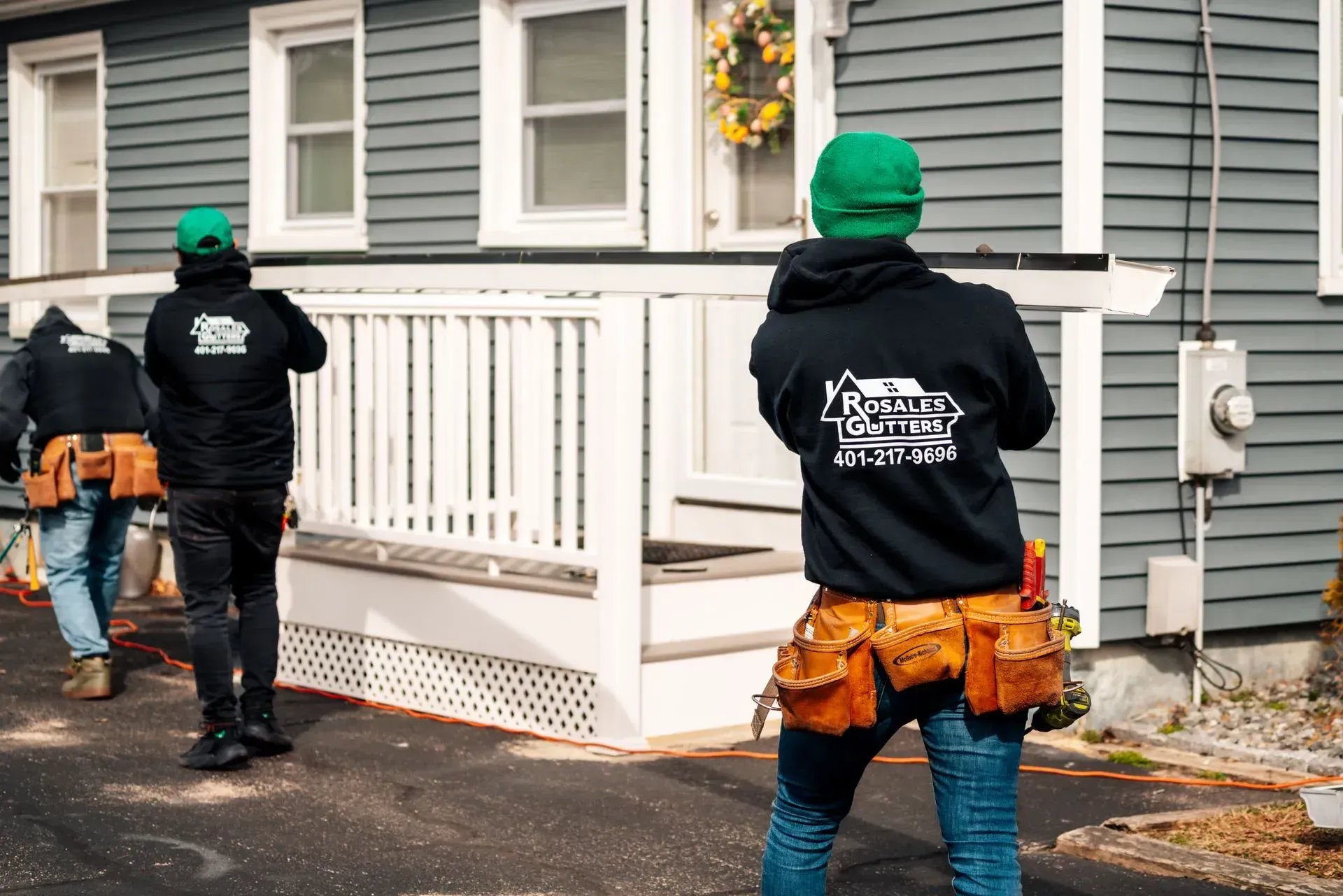 rosales gutters LLC workers moving a gutter in front of a house