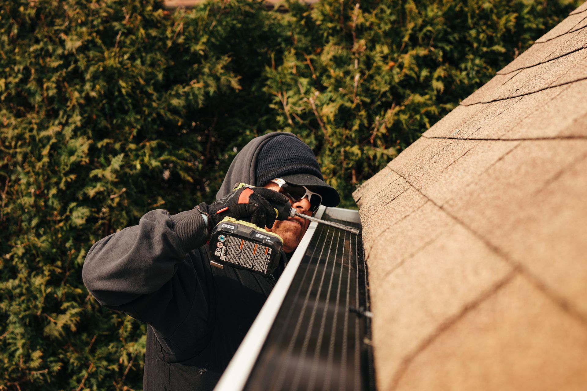 A man is installing solar panels on the roof of a house.