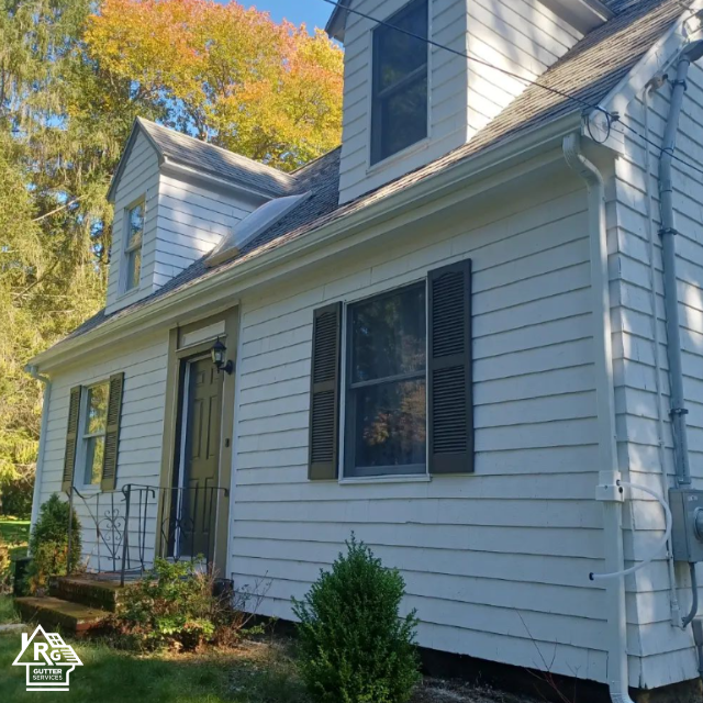 A white house with black shutters and a sign that says real estate