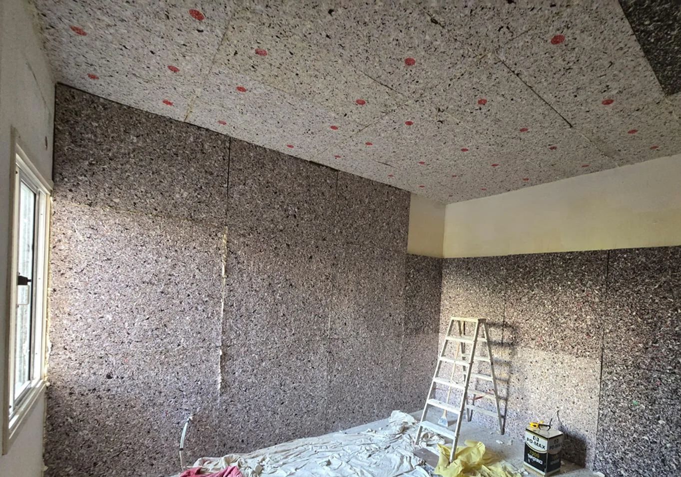 A man wearing a hard hat and goggles is standing in a room.