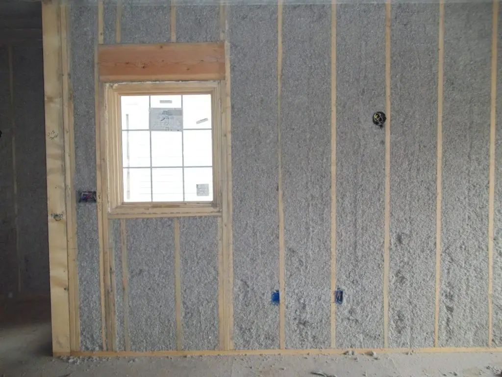 A man wearing a hard hat and goggles is standing in a room.