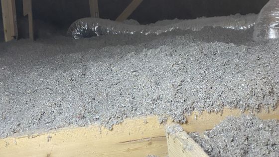 A construction worker wearing a blue hard hat is working on a roof