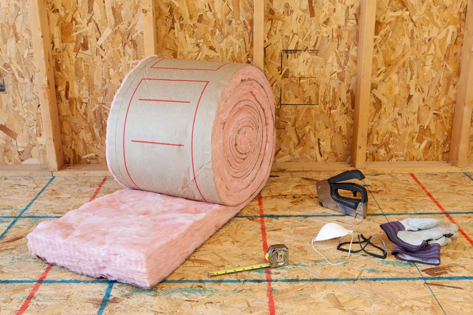 A man wearing a hard hat and goggles is standing in a room.