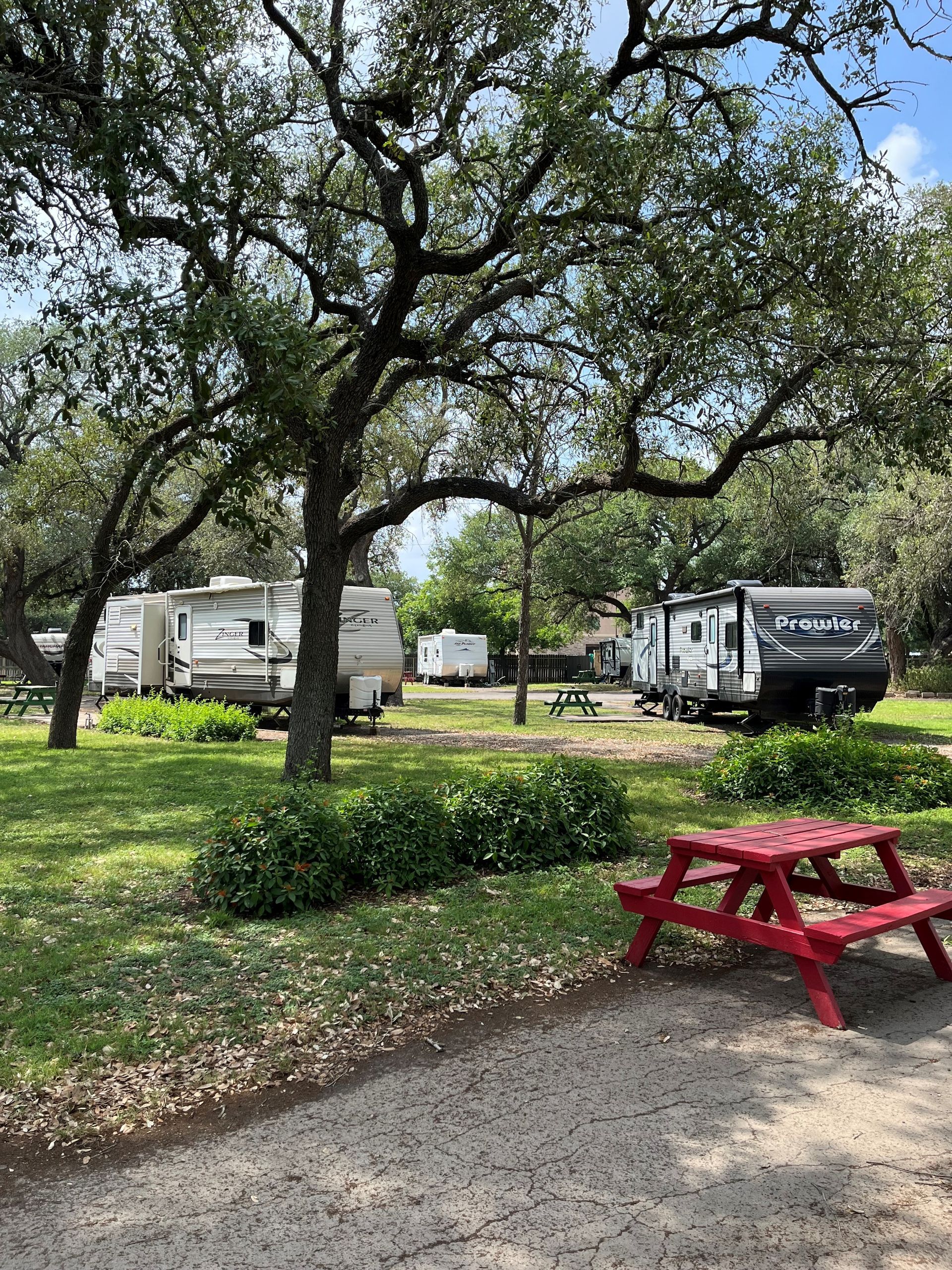 There is a red picnic table in the middle of a park.