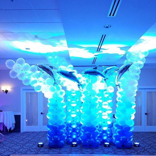 Blue balloon dolphin sculpture with white bubbles in a banquet hall, lit by blue lights