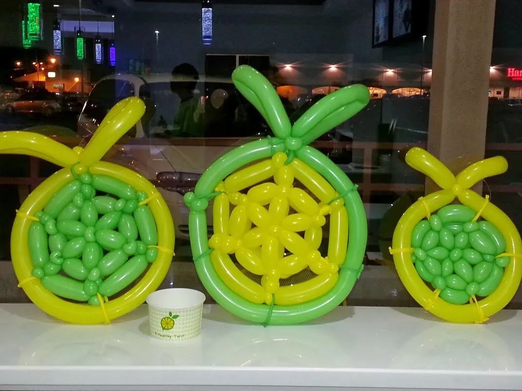 Three green balloon fruit sculptures with yellow centers displayed on a counter at night