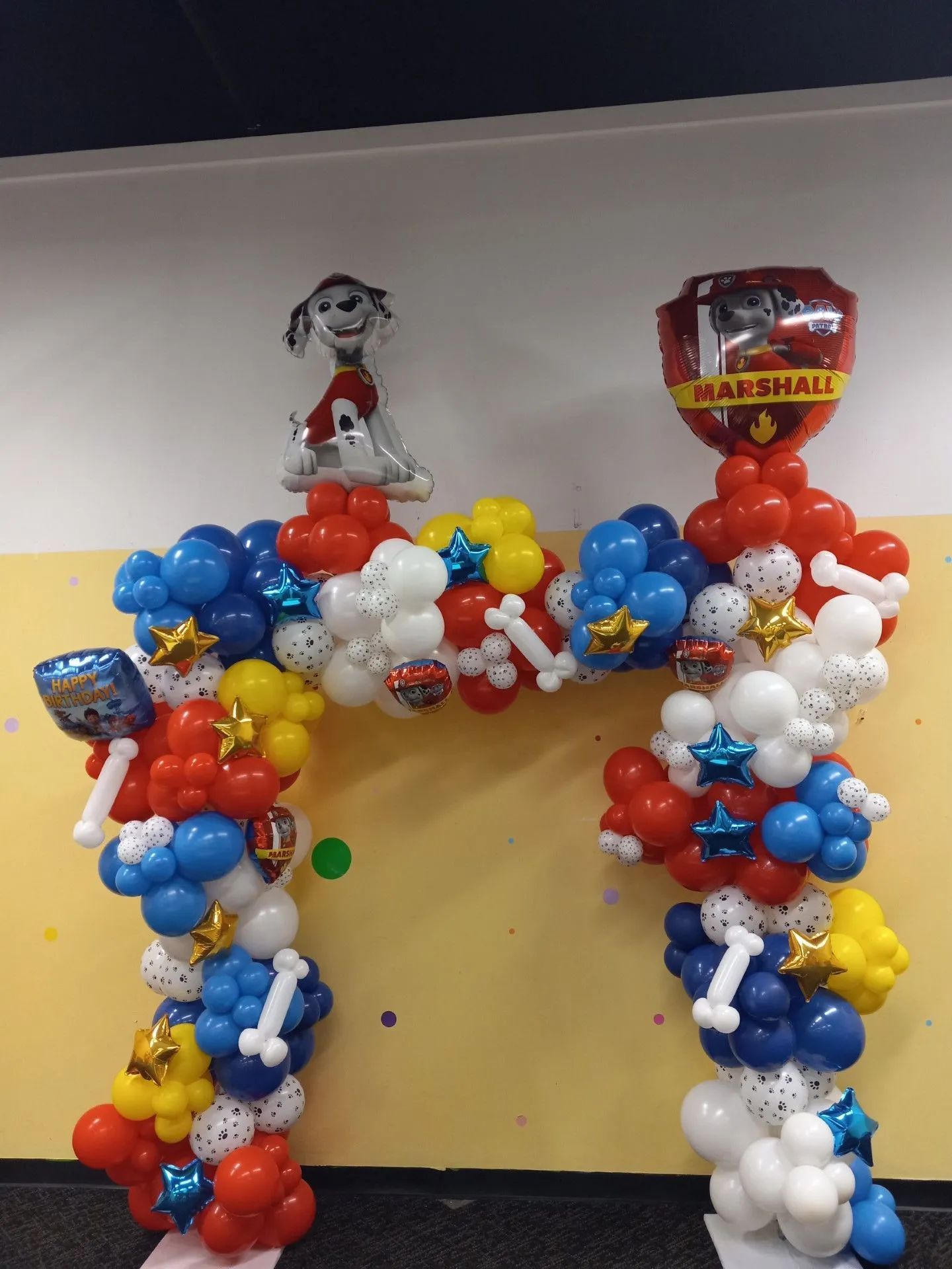 Balloon arch in red, white, and blue with Marshall Paw Patrol balloon topper at an event entrance