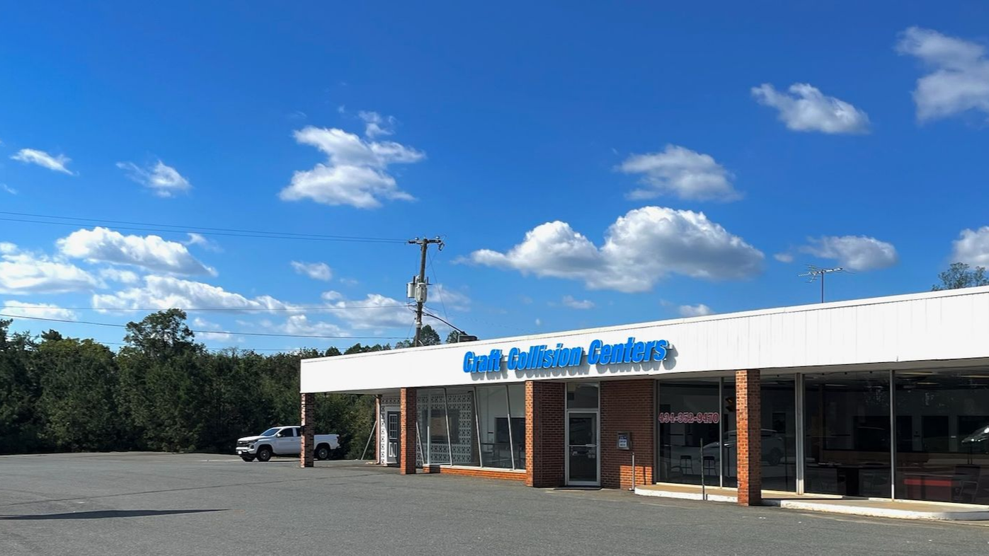 A white building with a blue roof and the words craft collision center on it.