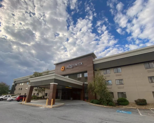 A large hotel with a parking lot in front of it.