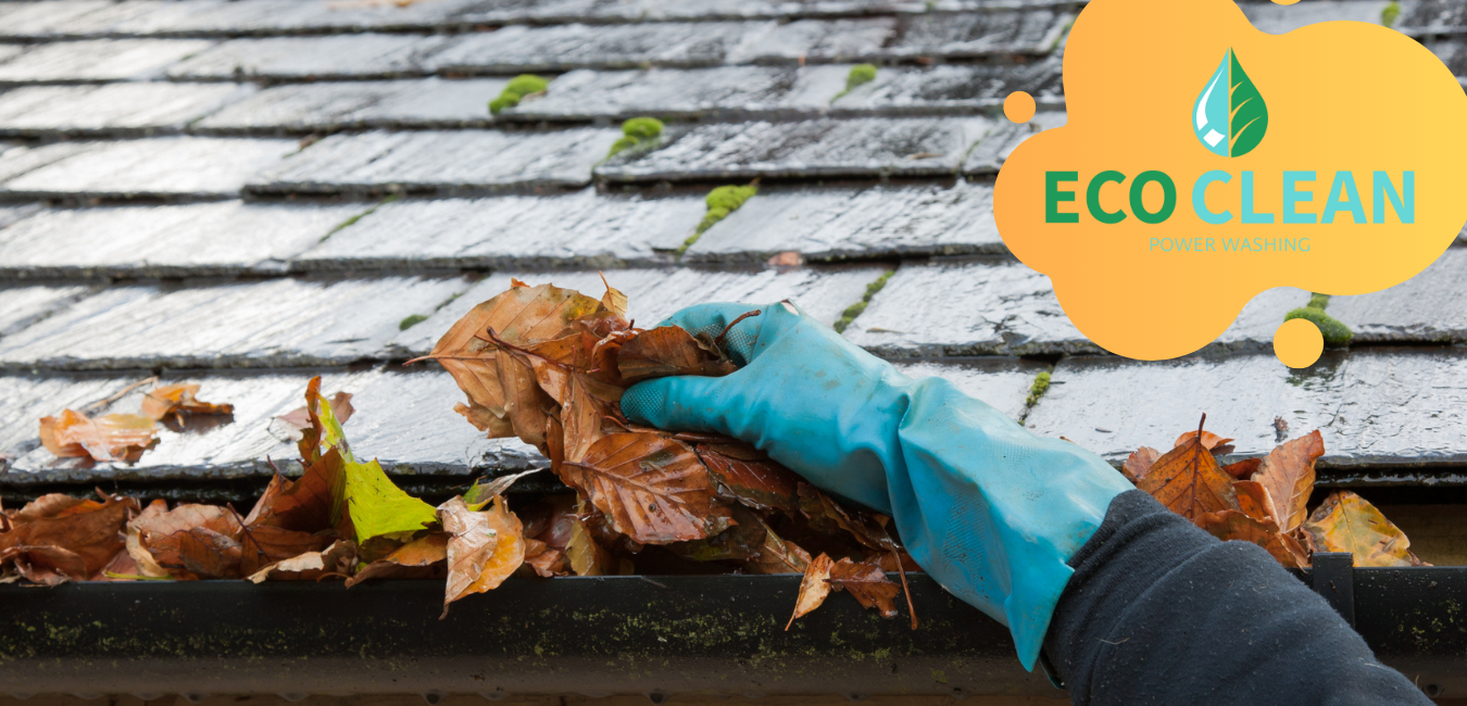 A person wearing rubber gloves is cleaning a gutter with leaves.