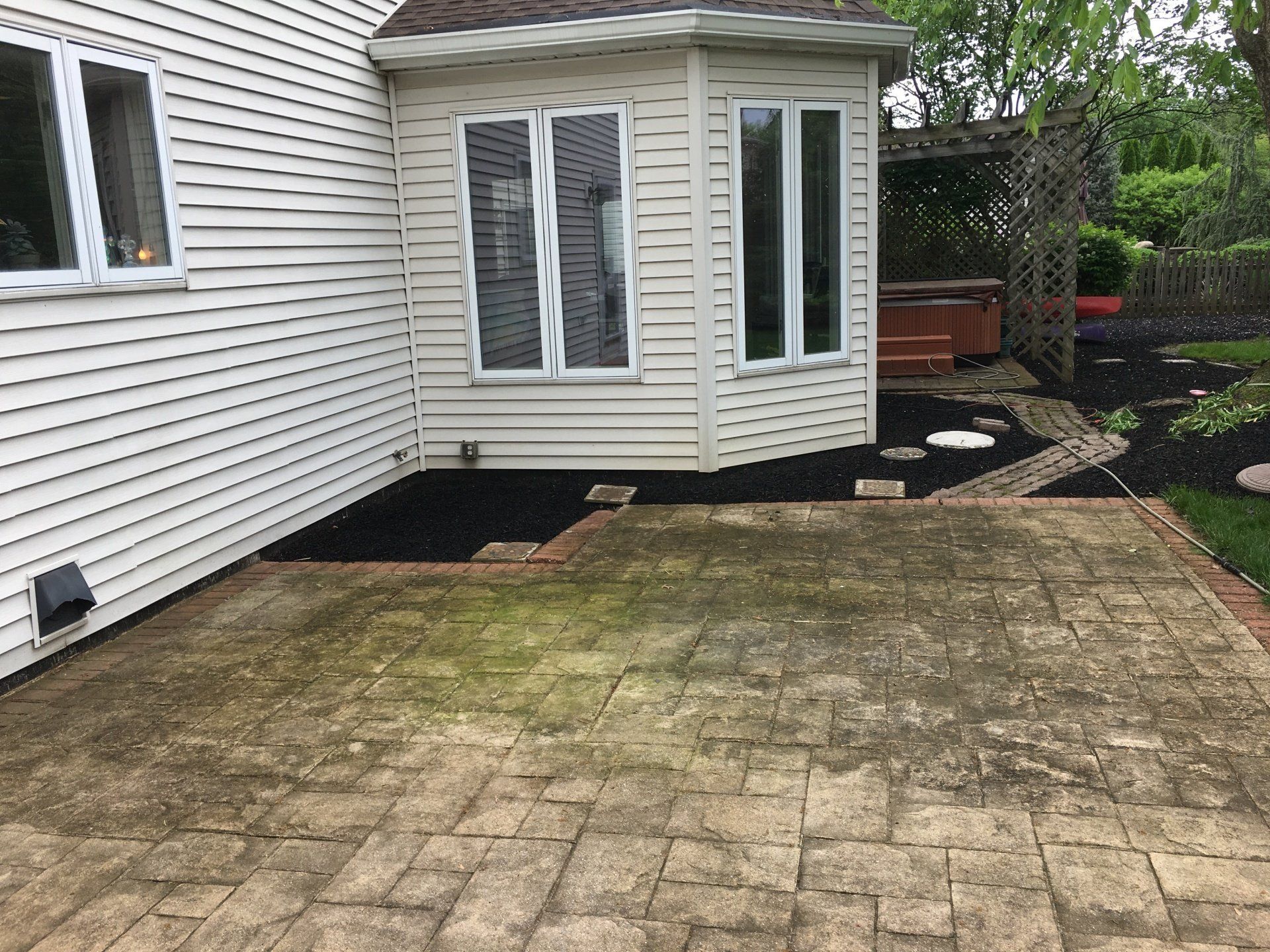 A backyard with a patio and a house in the background.