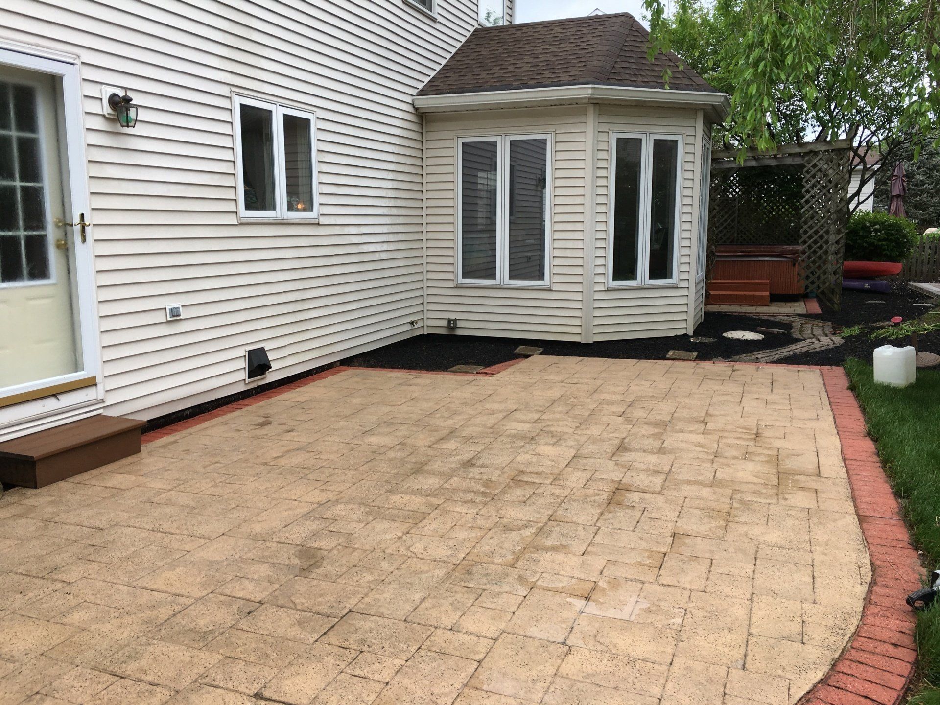 A backyard with a patio and a house in the background.