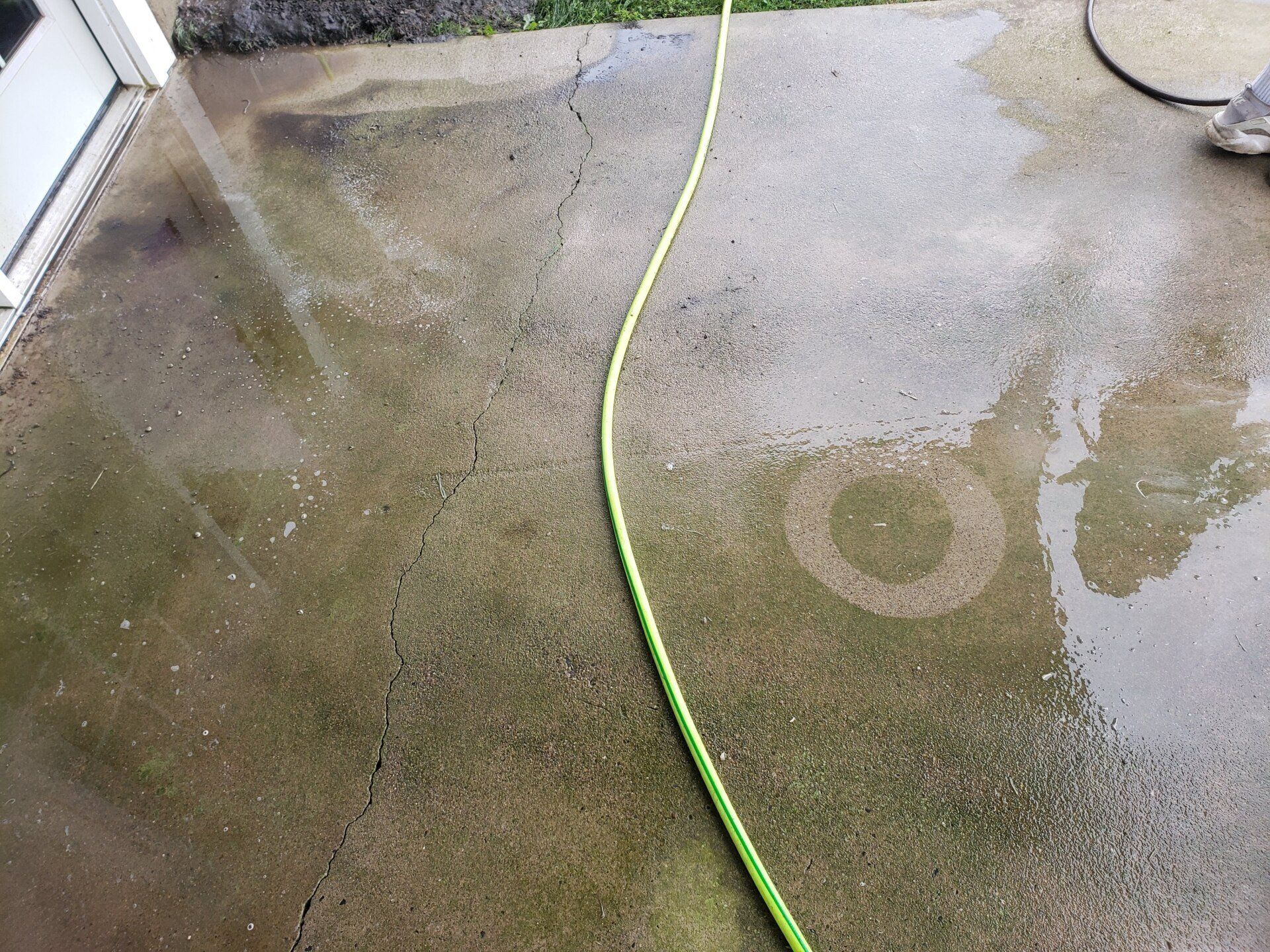 A green hose is being used to clean a concrete floor