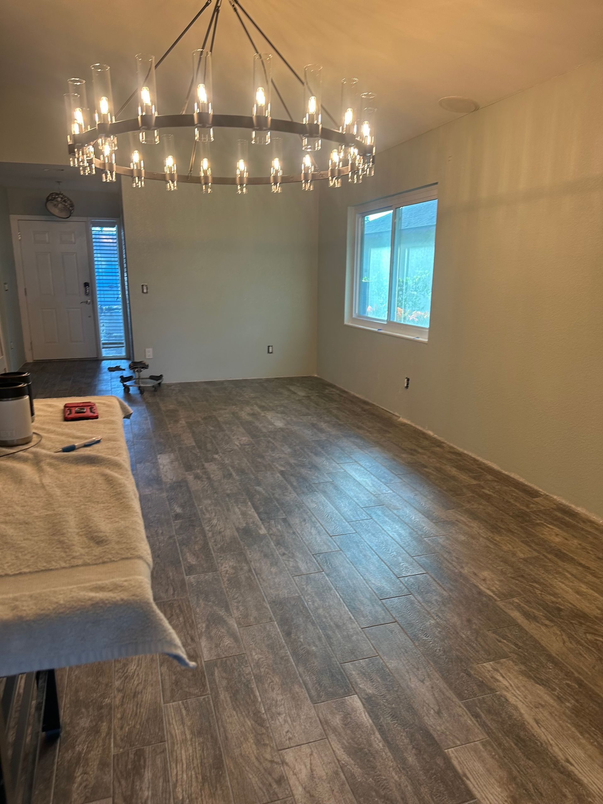 A room with wood floors, freshly painted walls, a chandelier, and a window.