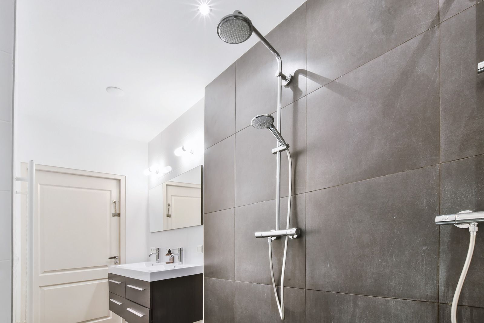 Person wearing glove using a trowel to apply grout to tile seams on a gray tiled floor.