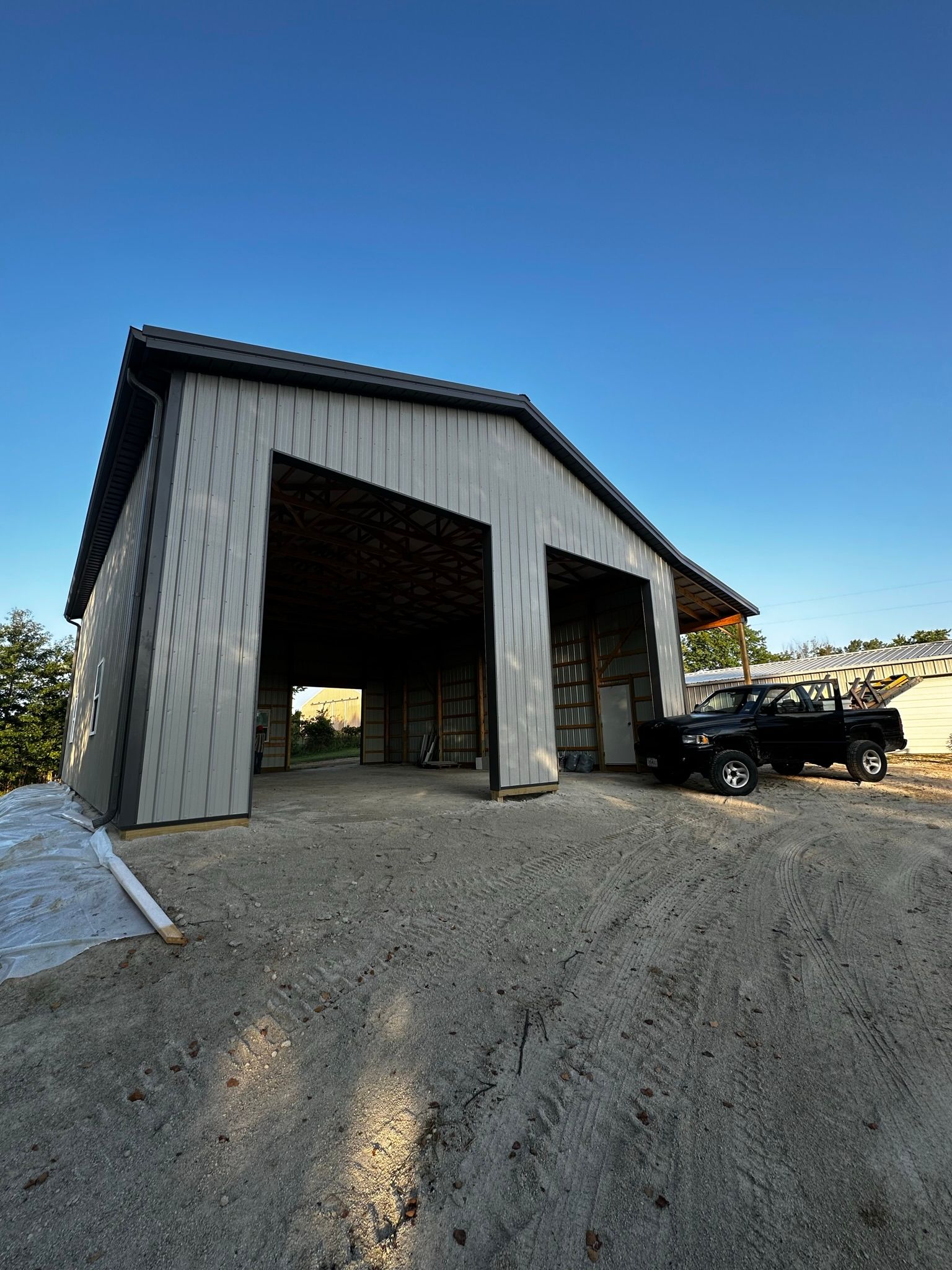 A black truck is parked in front of a large barn.