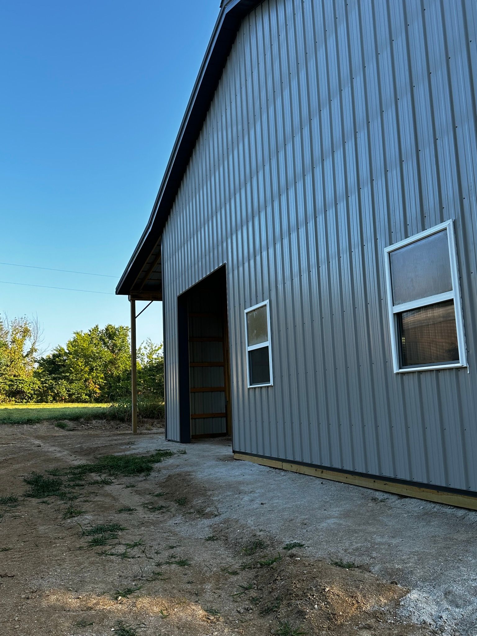 a gray barn with a large door and two windows