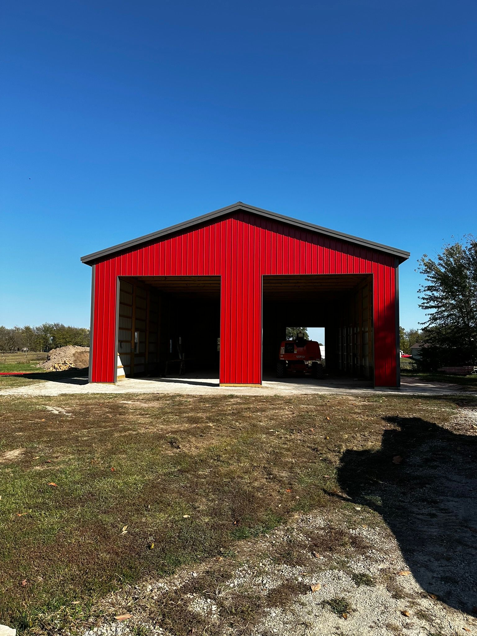 a red barn is sitting in the middle of a grassy field .