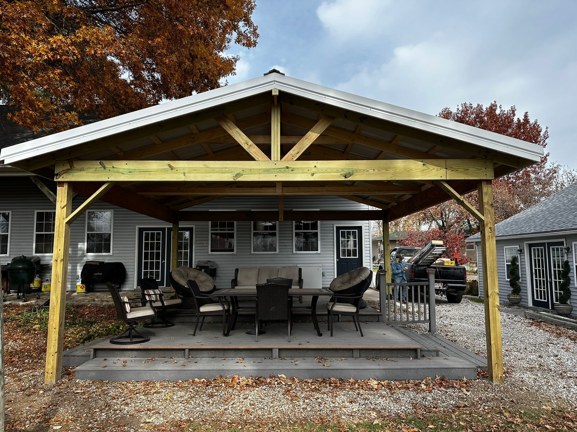 a wooden gazebo with a table and chairs underneath it is in front of a house .