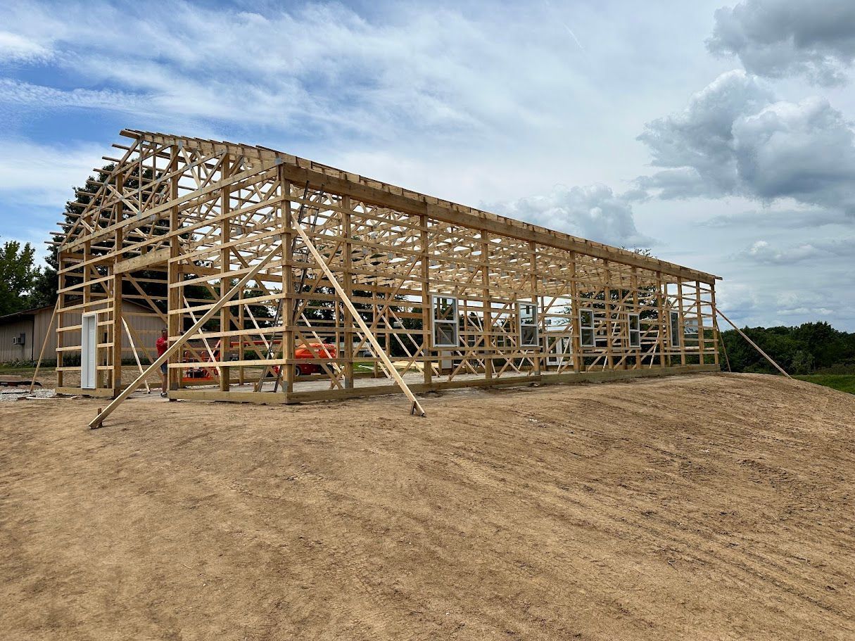 A large wooden structure is being built in a dirt field.
