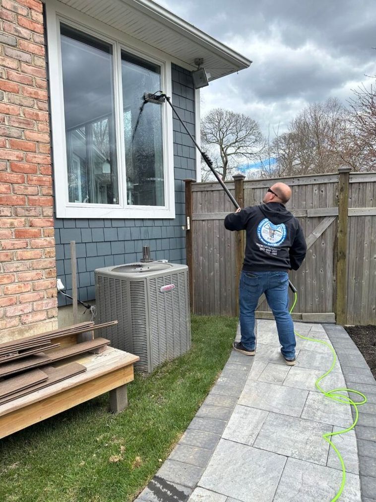 A man is cleaning the windows of a house with a high pressure washer.