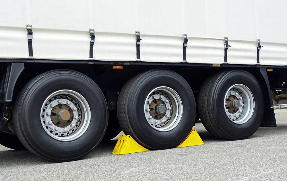 A Truck with Three Tires and A Yellow Wheel Chock — Petersen's Second Hand & New Tyres in Currajong, QLD