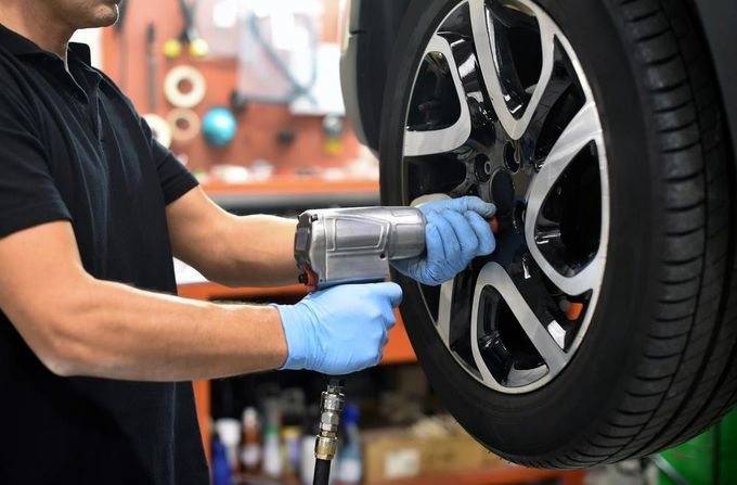 A Man Is Changing a Tire on A Car — Petersen's Second Hand & New Tyres in Currajong, QLD