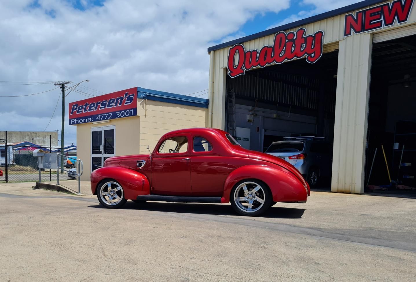 A Red Car Is Parked in Front of A Garage — Petersen's Second Hand & New Tyres in Currajong, QLD
