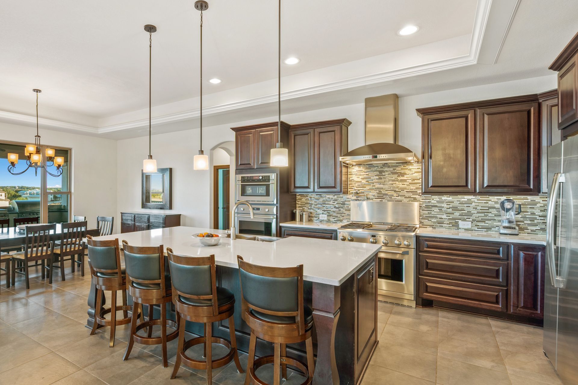 Spacious kitchen with a large island, dark wood cabinets, stainless steel appliances, and a dining table.