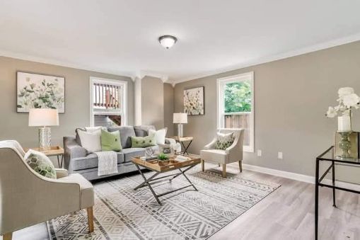 Living room with gray walls, sofa, chairs, rug, and artwork.
