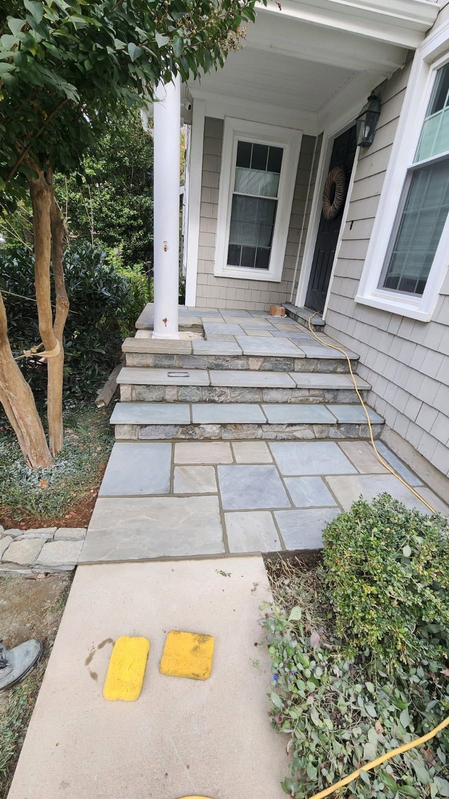 Stone steps and walkway leading to a house entrance. Includes steps, landscaping, and a partially visible person.